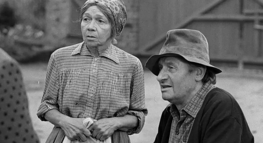 Marta Ławińska w stroju ludowym, obok mężczyzny w kapeluszu, w scenerii wiejskiej.