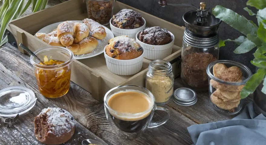 Idealny moment na fika w Szwecji: kawa, rogaliki, muffinki i ciasteczka w kształcie serc na drewnianej desce.