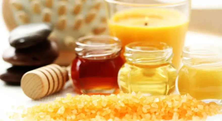 Ingredientes para un exfoliante casero para el cuerpo: sal, miel, aceites y una vela aromática.