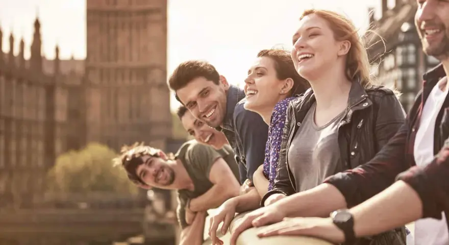 Glückliche Studenten genießen ihr Auslandssemester in England. Im Hintergrund ist das Parlament von London zu sehen.