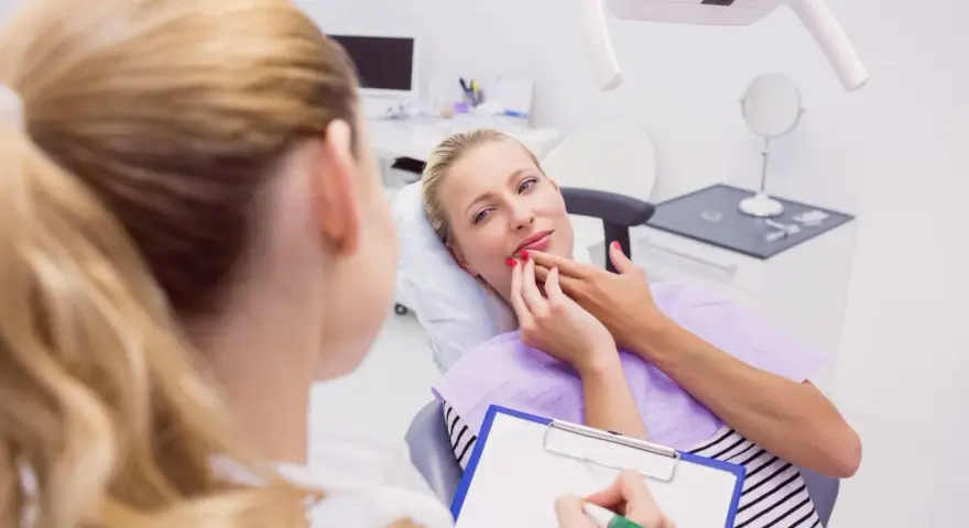 Kobieta w ciąży konsultuje z dentystką co na ból zęba w ciąży. Dentystka notuje na kartce.
