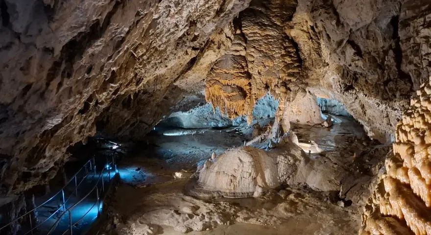 Wnętrze jaskiń w Zakopanem, z naciekami, stalaktytami i stalagmitami, oświetlone niebieskim światłem.