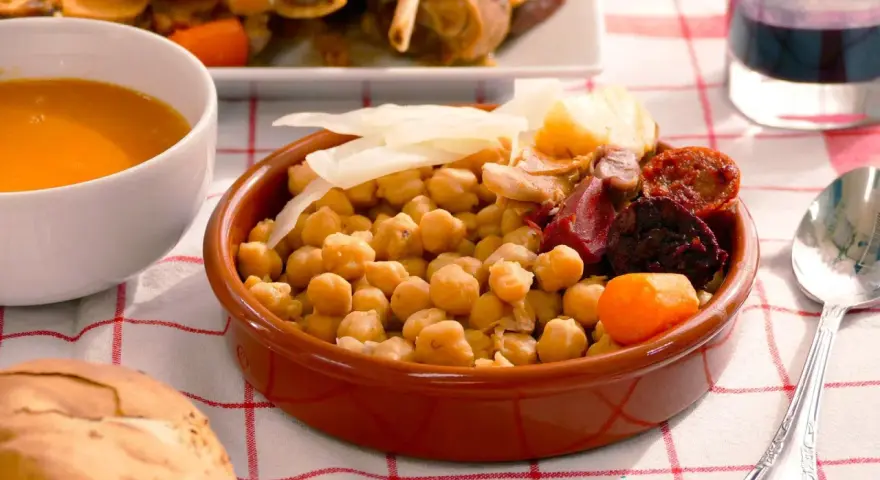 Cocido madrileño con garbanzos, chorizo, morcilla, patata y zanahoria en cuenco de barro.