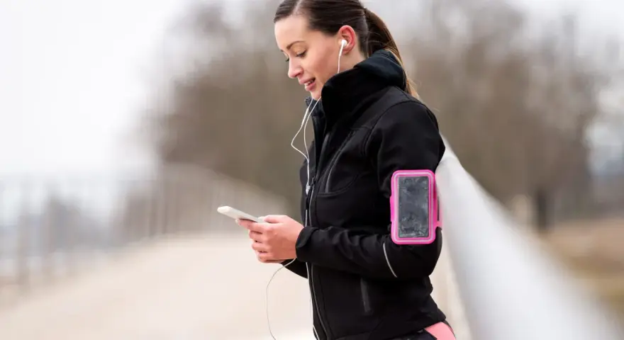 Donna con fascia da braccio rosa per il telefono, ideale per sapere dove mettere il telefono quando si corre.