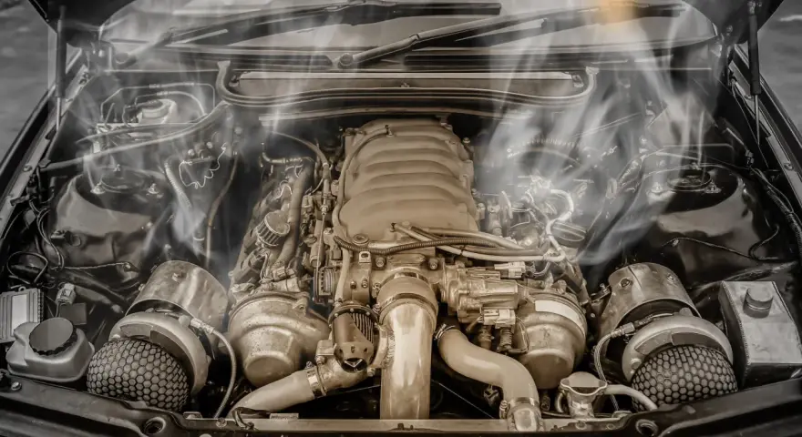 Smoke billows from a car's engine bay, indicating an engine overheating issue. The complex machinery sits idle, a testament to potential mechanical trouble.