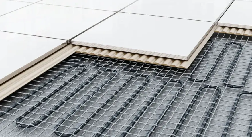 Coupe d'un sol carrelé montrant le système de chauffage au sol : câbles chauffants sous une couche isolante et un support, puis les carreaux.