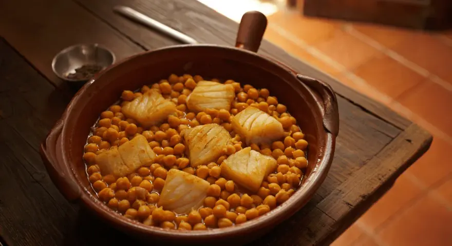 Guiso de garbanzos con trozos de bacalao en cazuela de barro.