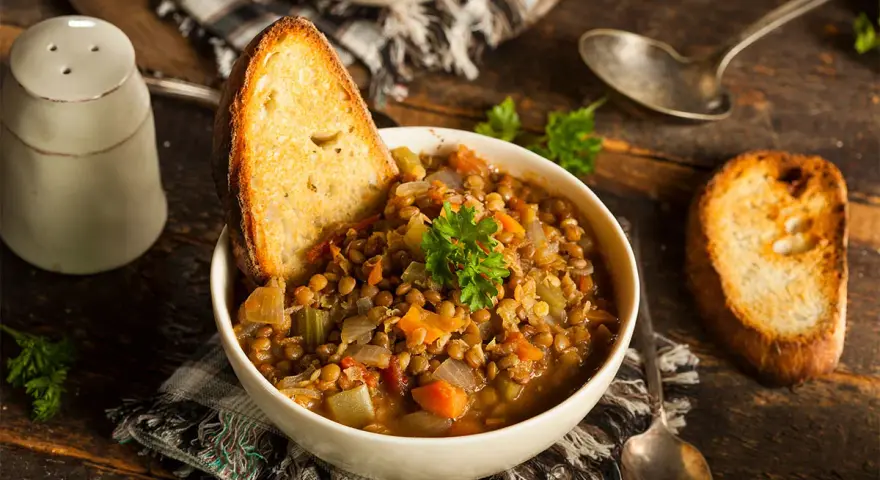 Zuppa di lenticchie ricca e saporita, servita con pane tostato e prezzemolo fresco. Un classico tra le ricette con lenticchie.