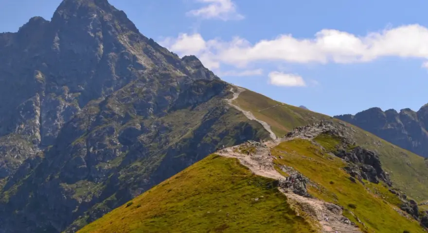 Kamienista ścieżka wije się po zielonych zboczach, prowadząc turystów ku majestatycznym tatry zachodnie szczyty.