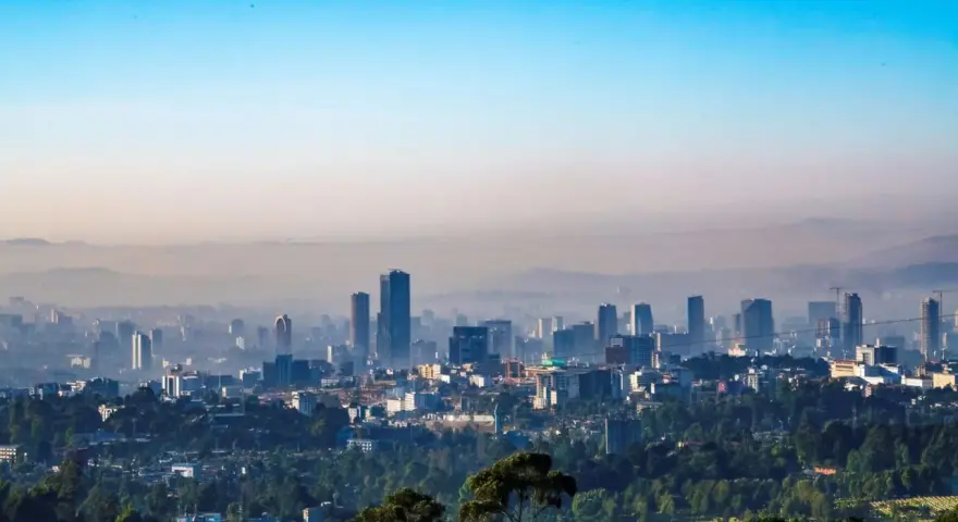Widok na rozległe miasto Addis Abeba, zdominowane przez nowoczesne wieżowce i otoczone zielenią.