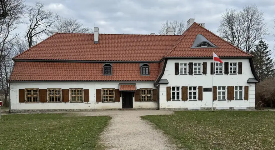 Dworek z czerwonym dachem i białymi ścianami, z polską flagą. Słychać tu echo gwary pomorskiej.