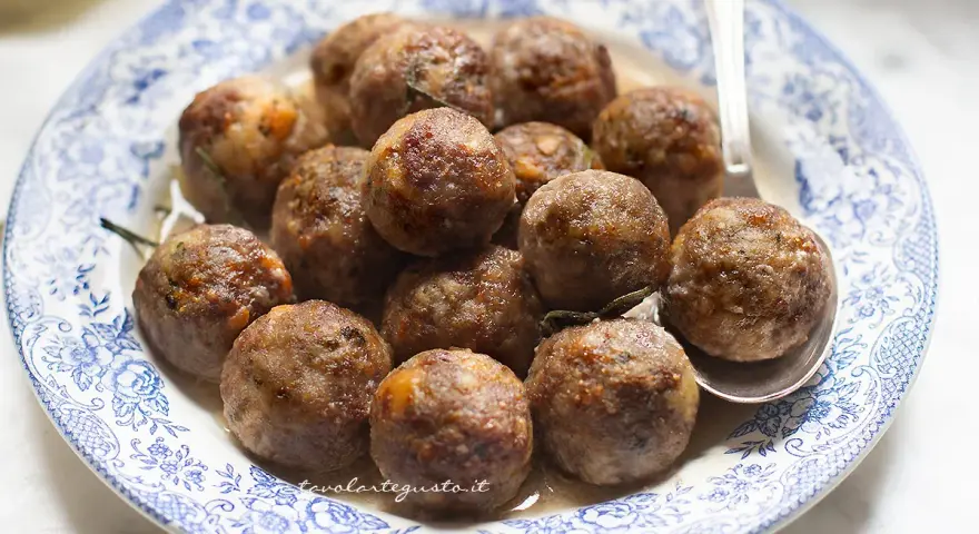 Polpette dorate e succulente in friggitrice ad aria, servite su un piatto con decori blu.