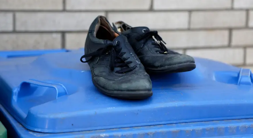 Stare buty na niebieskim koszu na śmieci. Zastanawiasz się, gdzie wyrzucać stare buty? To miejsce może być odpowiedzią.