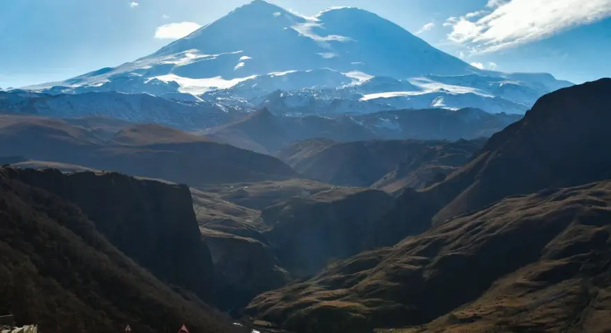 Majestatyczny Elbrus, najwyższy szczyt Europy, góruje nad doliną. Kręta droga prowadzi przez malownicze góry.