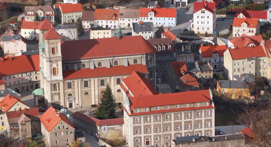 Widok z góry na miasteczko z czerwonymi dachami, w centrum imponujący kościół i zabudowania. To urokliwe bardo śląskie.