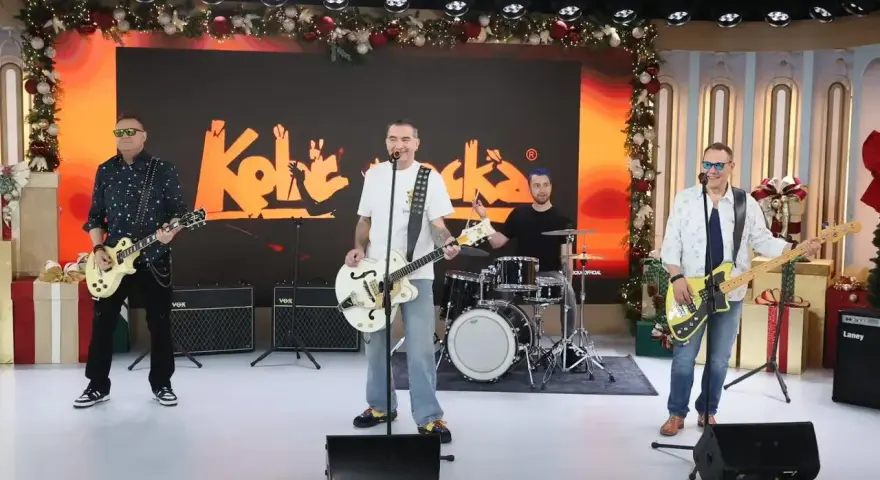 Zespół Kobranocka gra na scenie, w tle logo zespołu. Muzycy prezentują swoje utwory w świątecznej scenerii.