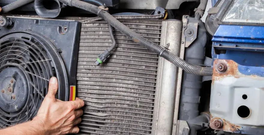 Mechanic inspects car's condenser, noting bent fins and corrosion, common symptoms of a bad condenser.