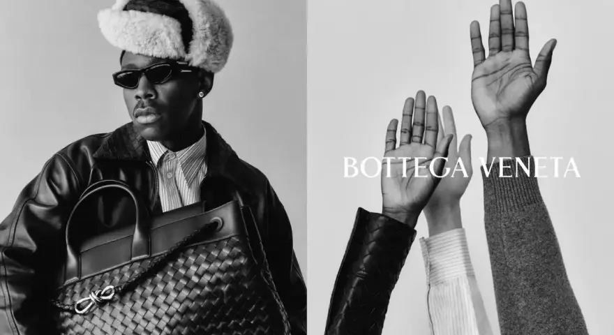 Uomo con cappello di pelliccia e borsa Bottega Veneta, mani alzate. Un omaggio alla storia del brand.