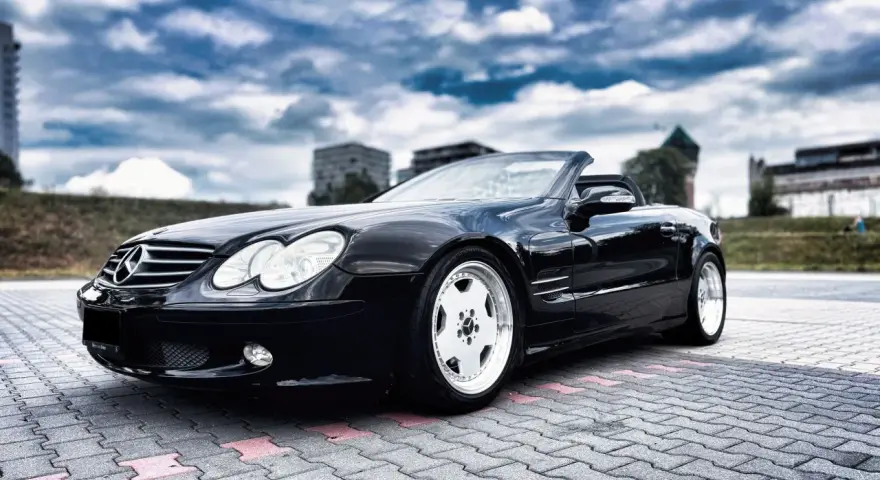 Czarny Mercedes SL R230 na parkingu. Nawet klasyki mają swoje **awarie i problemy**, ale ten wciąż wygląda świetnie.