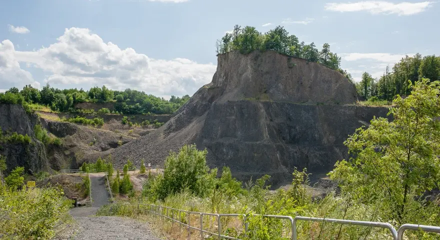 Kamieniołom przypomina wilczą górę, z której wyrasta bujna zieleń. Ścieżka prowadzi w głąb skalistego krajobrazu.