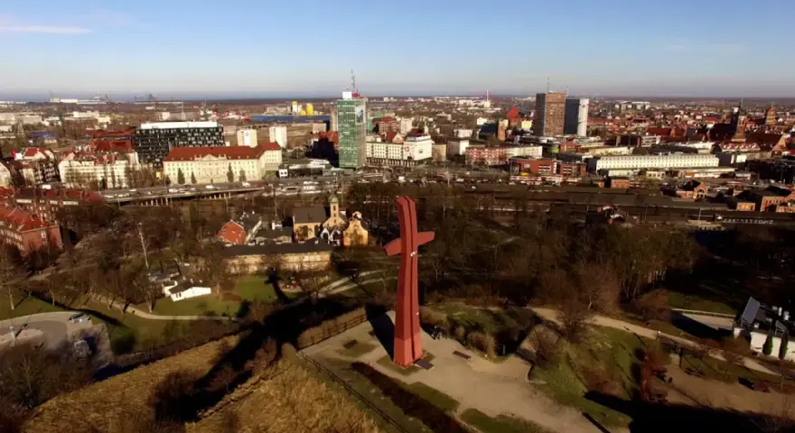 Góra Gradowa z czerwonym monumentem w kształcie krzyża na tle panoramy miasta.