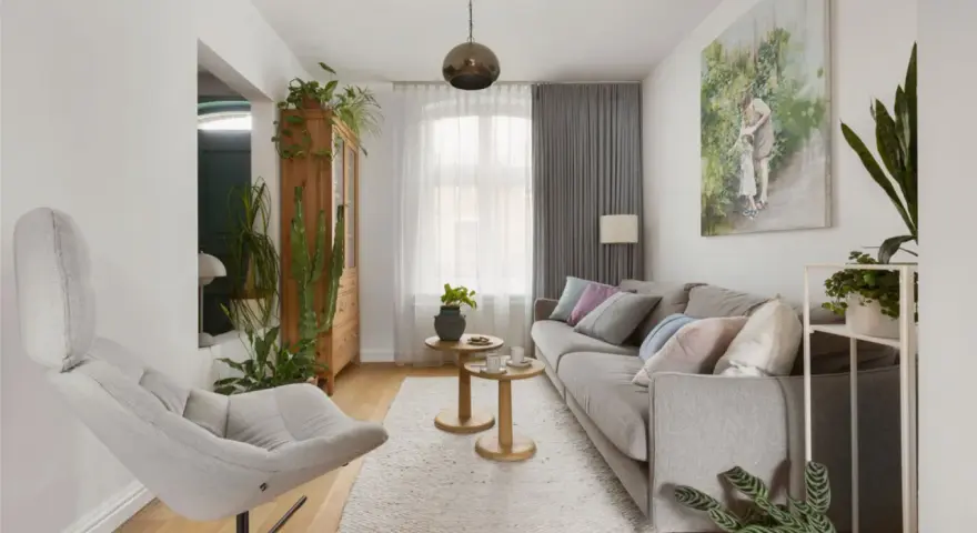 Przytulny salon w domu z szarą kanapą, wygodnym fotelem i mnóstwem zielonych roślin.