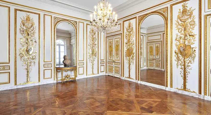 Salón dorado del museo Carnavalet, con suelo de parqué, candelabro de cristal y ornamentación dorada en las paredes.