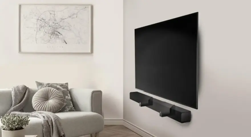Un elegante soggiorno con un divano grigio e un quadro astratto. Al centro, un televisore a schermo piatto montato a parete con una soundbar nera.