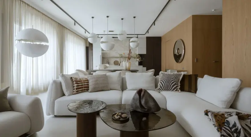 Nowoczesny projekt mieszkania z białą sofą, okrągłymi stolikami i designerskimi lampami.
