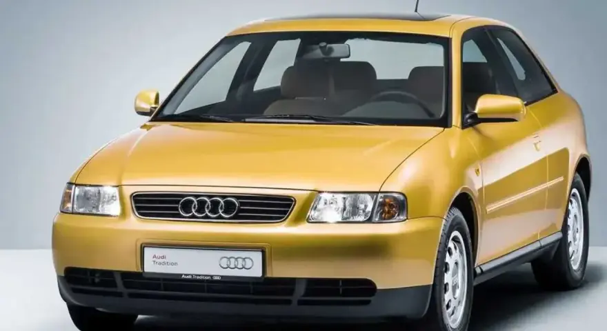Gelber Audi A3 Baujahr 2000, dreitürig, mit Schiebedach und dem Schriftzug "Audi Tradition".