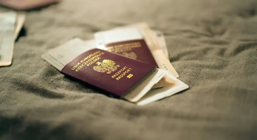 Kilka paszportów leży na szarym materiale. Zastanawiasz się, ile czeka się na paszport w Polsce?