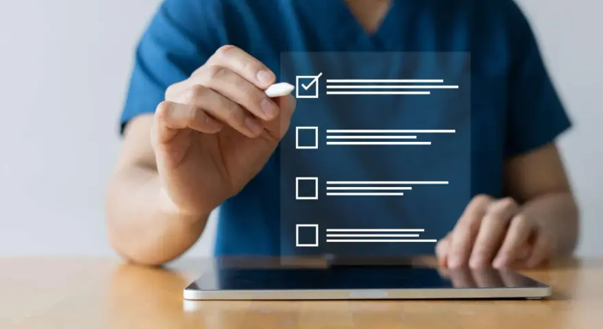 Dłoń zaznacza ptaszkiem pierwszy element na liście kontrolnej wyświetlanej na ekranie tabletu.