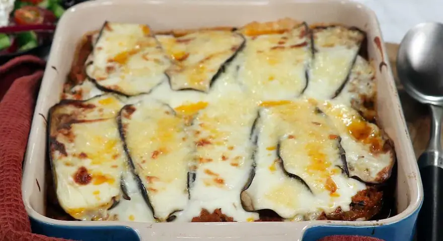 En ugnsform med en gyllene, bubblande moussaka, redo att serveras. Perfekt för ett mysigt middagsrecept.