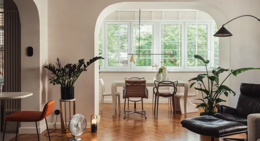 Eklektyczny salon z jadalnią, gdzie nowoczesne meble i rośliny tworzą przytulną atmosferę.