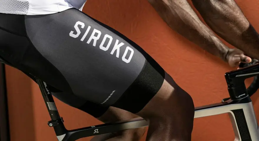 En cyklist med synliga cykling muskler på benen, klädd i svarta cykelbyxor med texten "SIROKO".