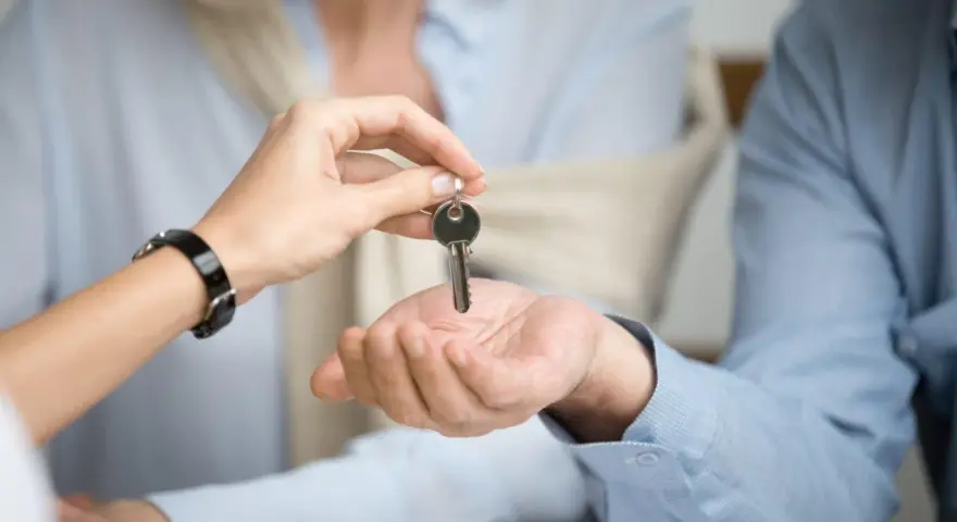 Una mano entrega una llave a otra, simbolizando el inicio de un nuevo hogar. Considera qué tener en cuenta al alquilar un piso.