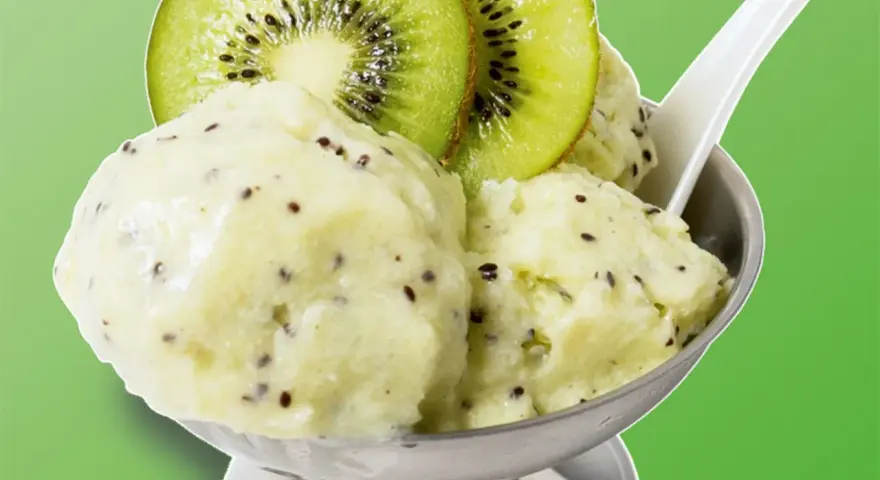 Erfrischendes Kiwi-Eis in einer Schale, garniert mit frischen Kiwischeiben. Ein Löffel steckt darin, bereit zum Genuss.