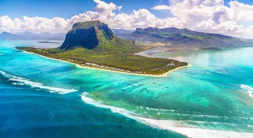 Mauritius pogoda październik: turkusowa woda, zielona góra Le Morne Brabant i białe chmury. Idealna pogoda na rajskie wakacje.