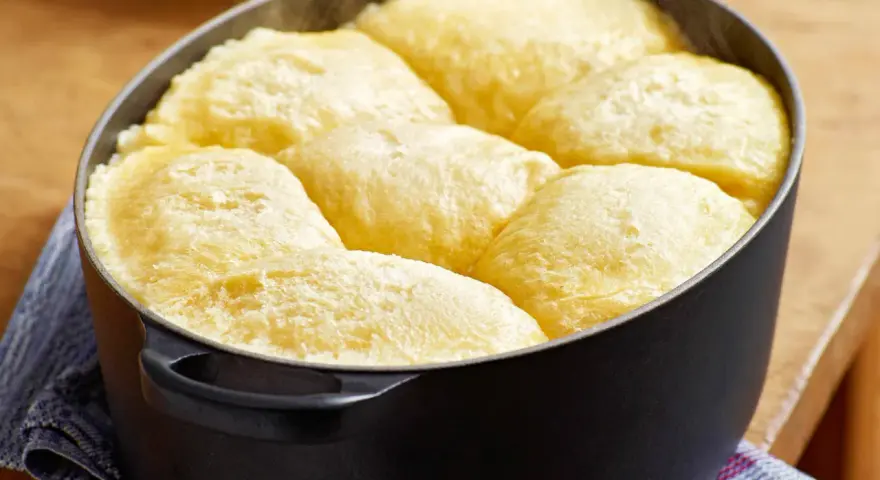 Frisch gebackene Dampfnudeln in einem schwarzen Topf. Ein köstliches Dampfnudel Rezept, das du unbedingt ausprobieren musst!