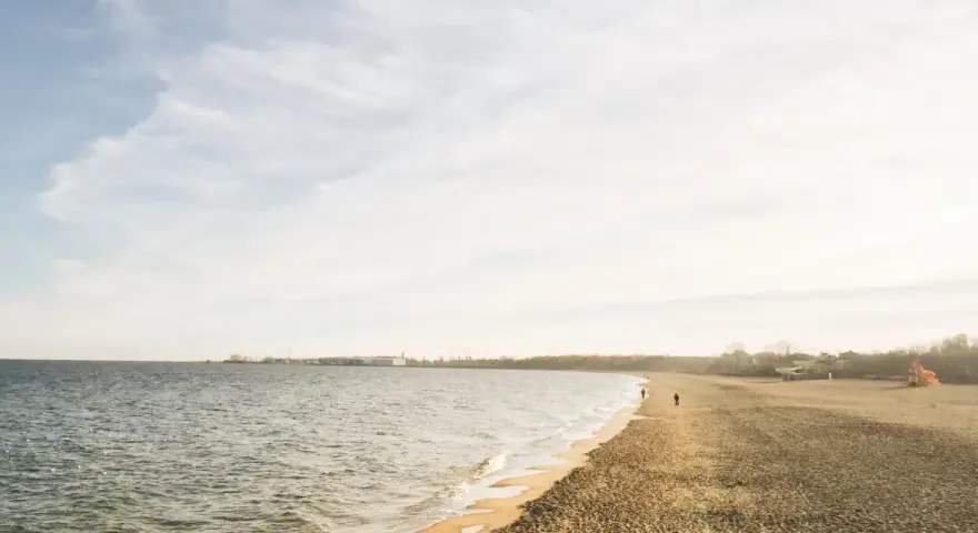 Spokojny dzień nad morzem na Kaszubach. Pusta plaża, delikatne fale i kilka osób spacerujących brzegiem.