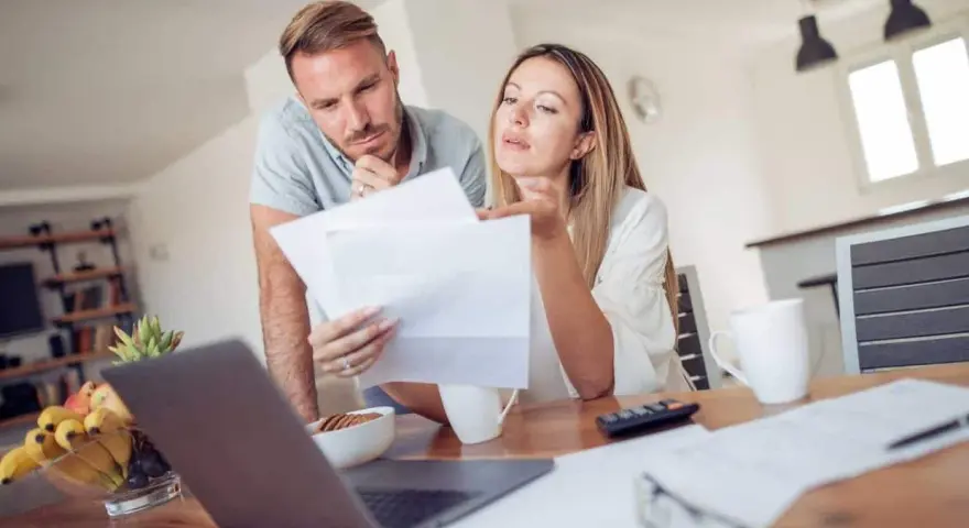 Couple discutent de documents, peut-être une pacs déclaration séparée, devant un ordinateur portable.