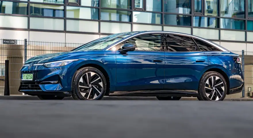 Niebieski Volkswagen ID.7 zaparkowany przed nowoczesnym budynkiem.