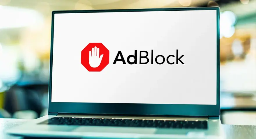 Laptop z logo AdBlock. Dowiedz się, jak wyłączyć adblocka, aby zobaczyć treści.