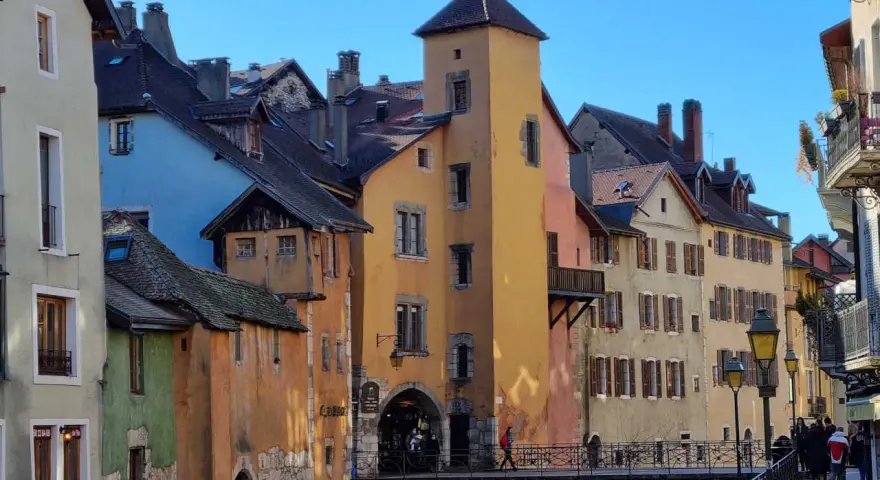 Magnifique journée pour visiter Annecy à pied. Les maisons colorées bordent le canal, un pont de pierre relie les rives.
