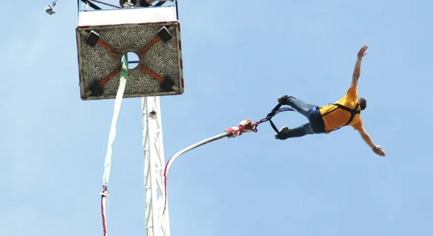 Mężczyzna w żółtej koszulce skacze na bungee. Zastanawiasz się, ile kosztuje skok na bungee?
