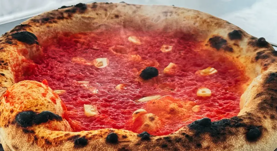 Heiß dampfende Pizza mit knusprigem Rand und leckerer marinara sauce, belegt mit Knoblauch und Oliven.
