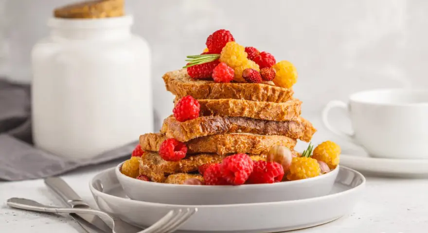 Gestapelte Scheiben Brot, garniert mit Himbeeren und gelben Beeren, perfekt zum Backen mit Hafermilch.