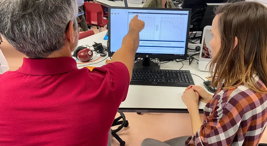 Un homme montre un audiogramme sur un écran, peut-être lors d'une formation pour obtenir son diplôme d'audioprothésiste en Espagne.