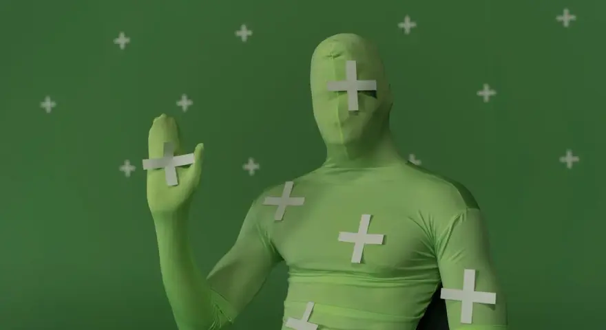 Persona in tuta verde con croci bianche, pronta per effetti speciali. Ecco come si usa il green screen per trasformare la realtà.