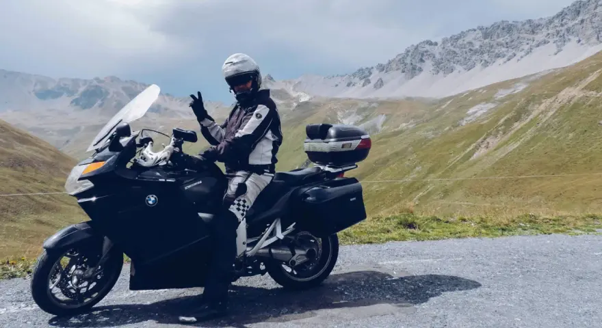 Motocyklista w kasku pozdrawia na tle gór. Przełęcz Stelvio zamknięta, ale widoki zapierają dech w piersiach.